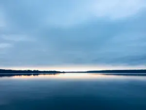 Calm lake and reflected sky representing steadiness, recovery and emotional regulation.